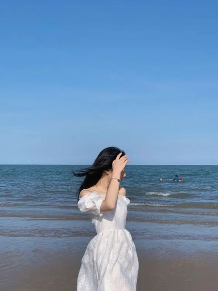 Tạo dáng đứng với bộ váy trắng khi chụp ảnh trên biển