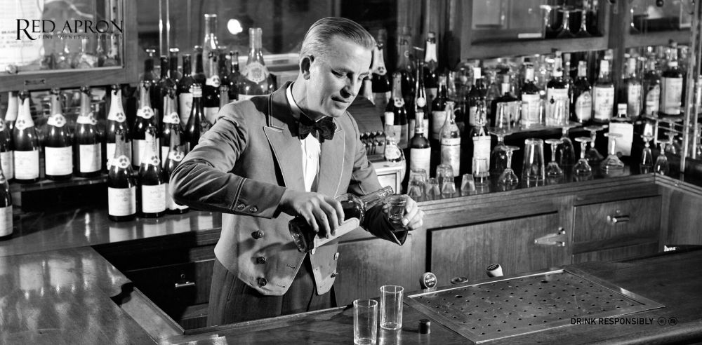 Bartender pha Old Fashioned theo phong cách cổ điển tại quầy bar với ly rocks và whisky