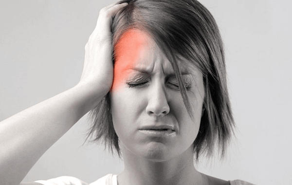 Người phụ nữ ôm đầu, nhăn mặt vì cơn đau nửa đầu