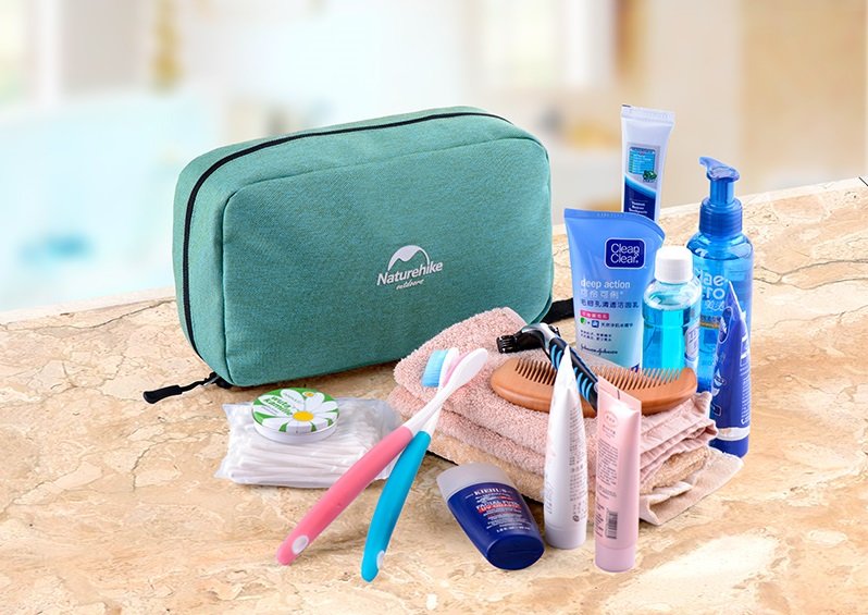 Túi đựng đồ cá nhân đi du lịch dáng hộp XSB01 màu xanh lá được đặt cạnh các loại mỹ phẩm