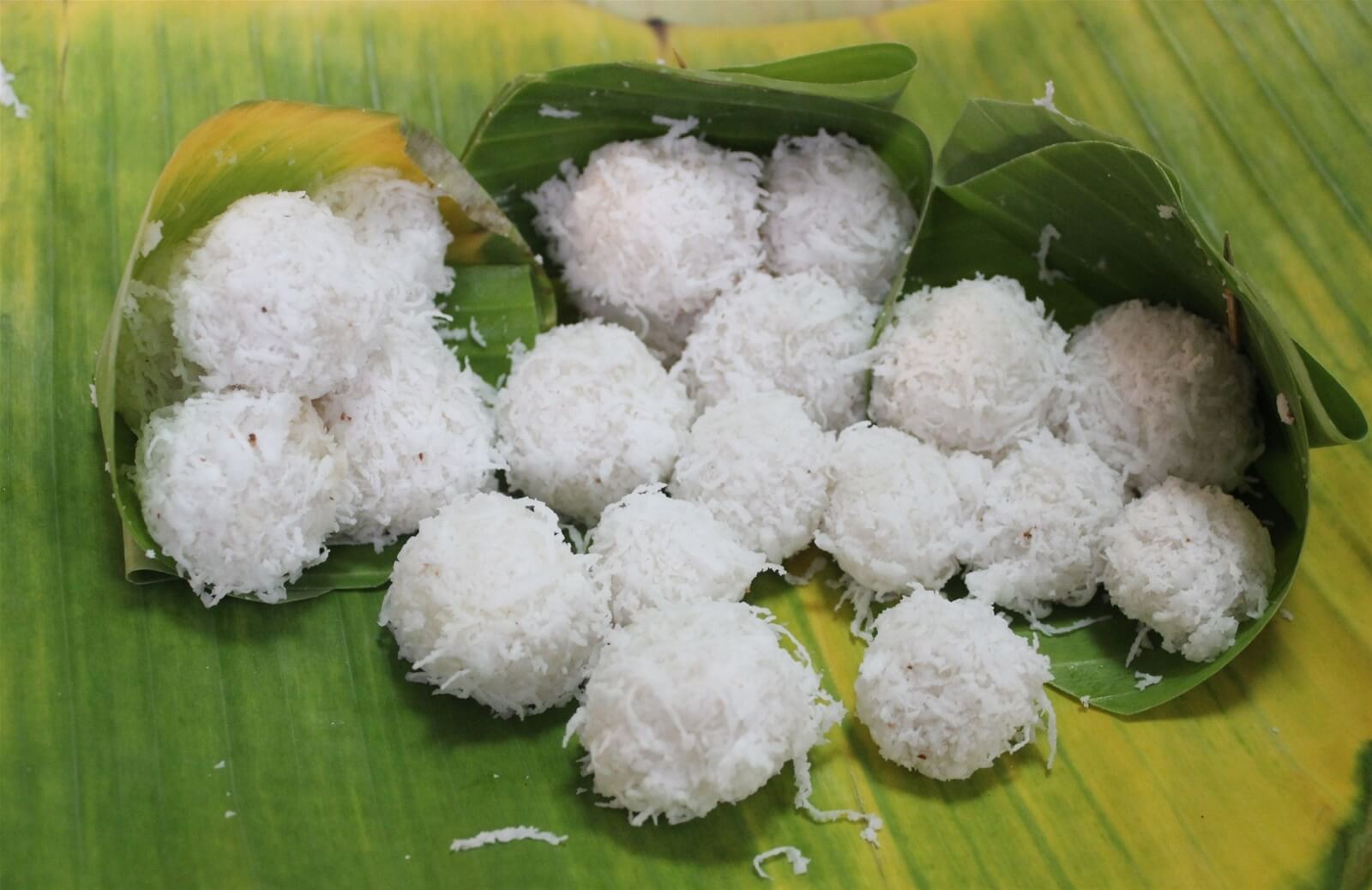 Những viên bánh gạo nhỏ, màu trắng màu cơm dừa thái sợi được đặt trên tấm lá chuối xanh