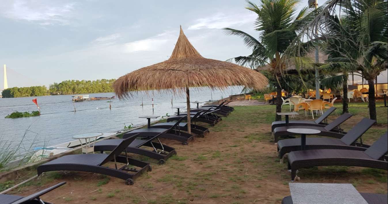 Bãi biển nhân tạo Cần Thơ với nhiều ghế nghỉ mát có ô trên bờ cùng những rặng dừa xanh mát