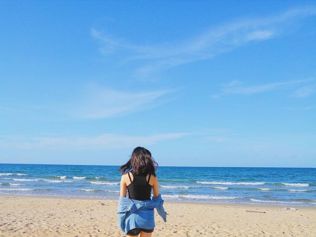 Biển Thuận An yên bình, lặng sóng, nước trong xanh có bạn nữ đang chụp ảnh trên bãi cát trắng