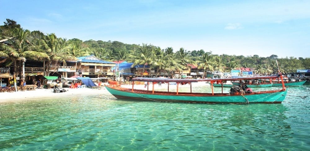 Những ngôi nhà nhỏ trên đảo Koh Rong bên cạnh dòng nước biển trong xanh, có nhiều thuyền đang đỗ