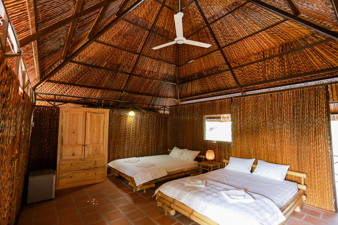 Phòng ngủ của Hometravel Mekong Cần Thơ có 2 chiếc giường màu trắng, 1 quạt trần