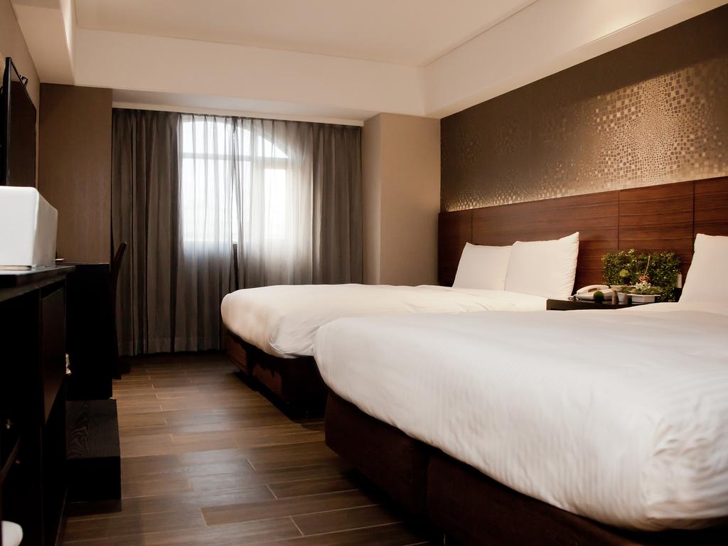 Phòng ngủ sạch đẹp với 2 chiếc giường trắng, có cửa sổ ở KDM Hotel, Đài Bắc