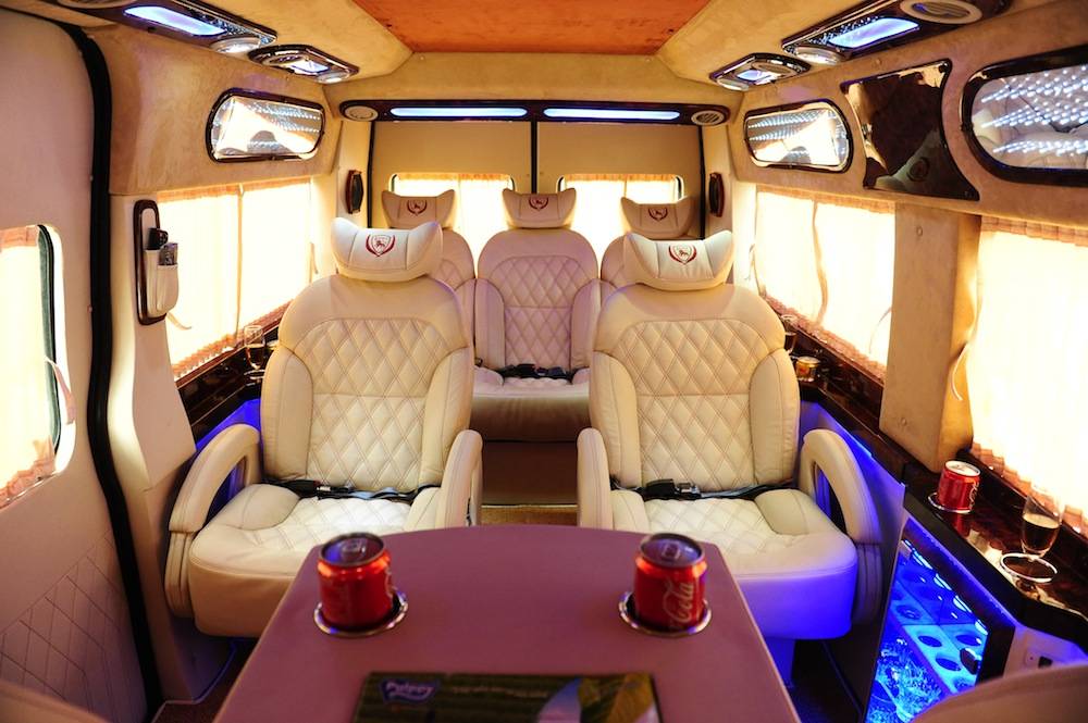 Bên trong xe Limousine đầy đủ tiện nghi với ghế nằm trắng, bàn để đồ