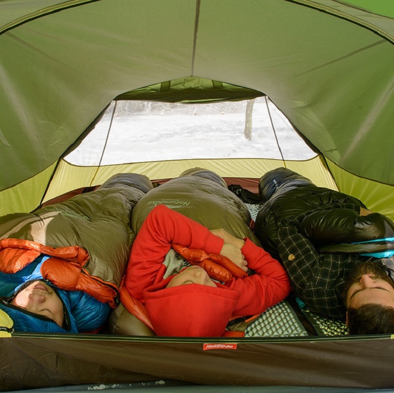 3 người sử dụng túi ngủ nằm nghỉ thơi thoải mái trong phòng ngủ của lều