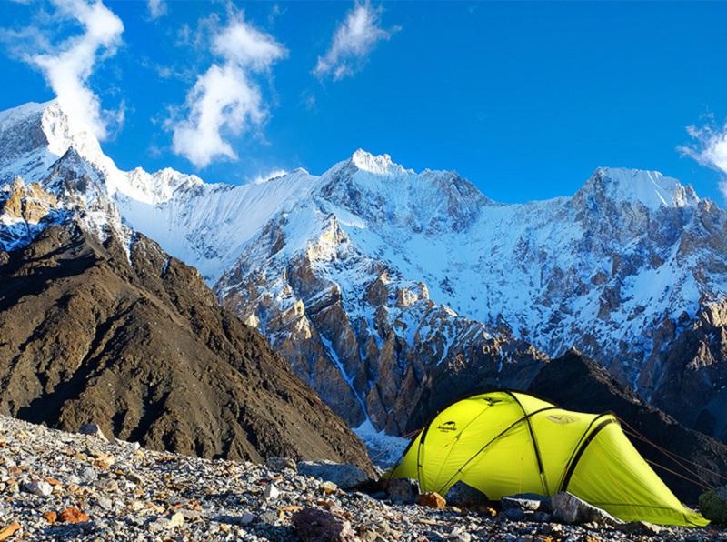 Lều cắm trại màu vàng được dựng trên đỉnh núi đầy sỏi đá
