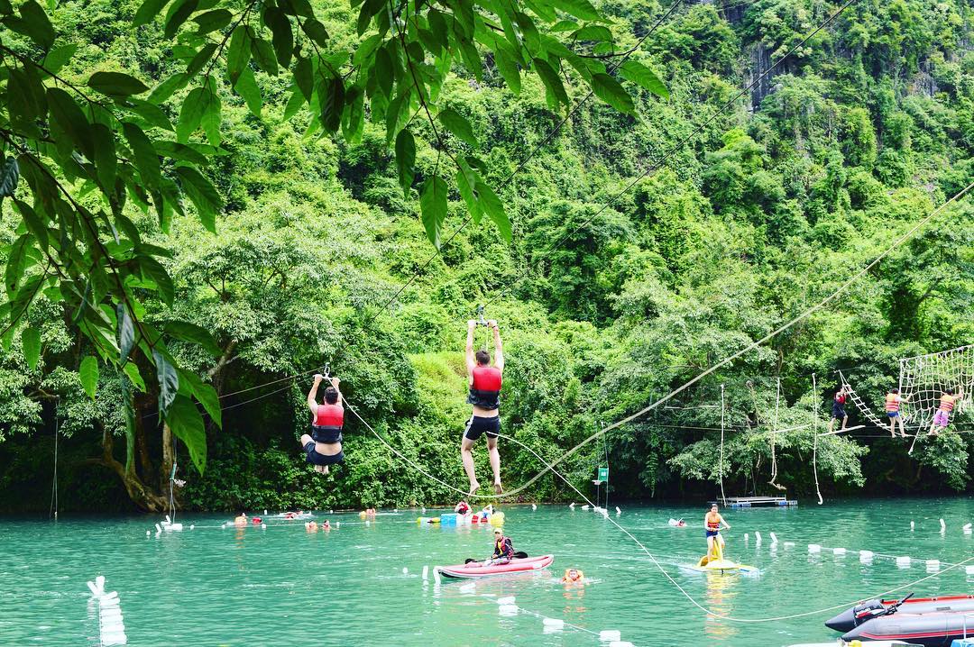 Khu du lịch sinh thái Sông Chày - Hang Tối có nhiều du khách mặc áo phao đang tham gia các trò chơi dưới nước: đu dây, zipline, chèo kayak
