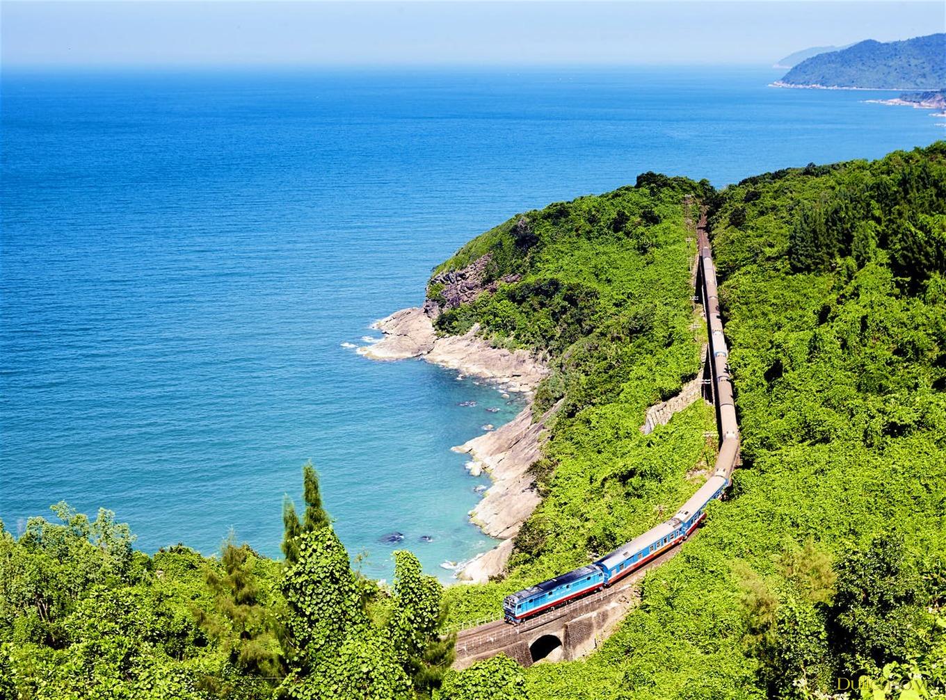 Tàu hoả đang đi trên tuyến đường đến Ninh Thuận, xung quanh là đồi núi xanh mênh mông và biển trong xanh bao bọc