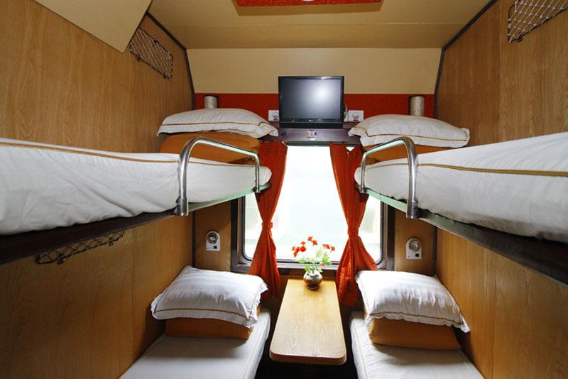Khoang tàu hoả TSC Express có 4 giường chăn gối trắng tinh và TV, cửa sổ nhìn ra ngoài