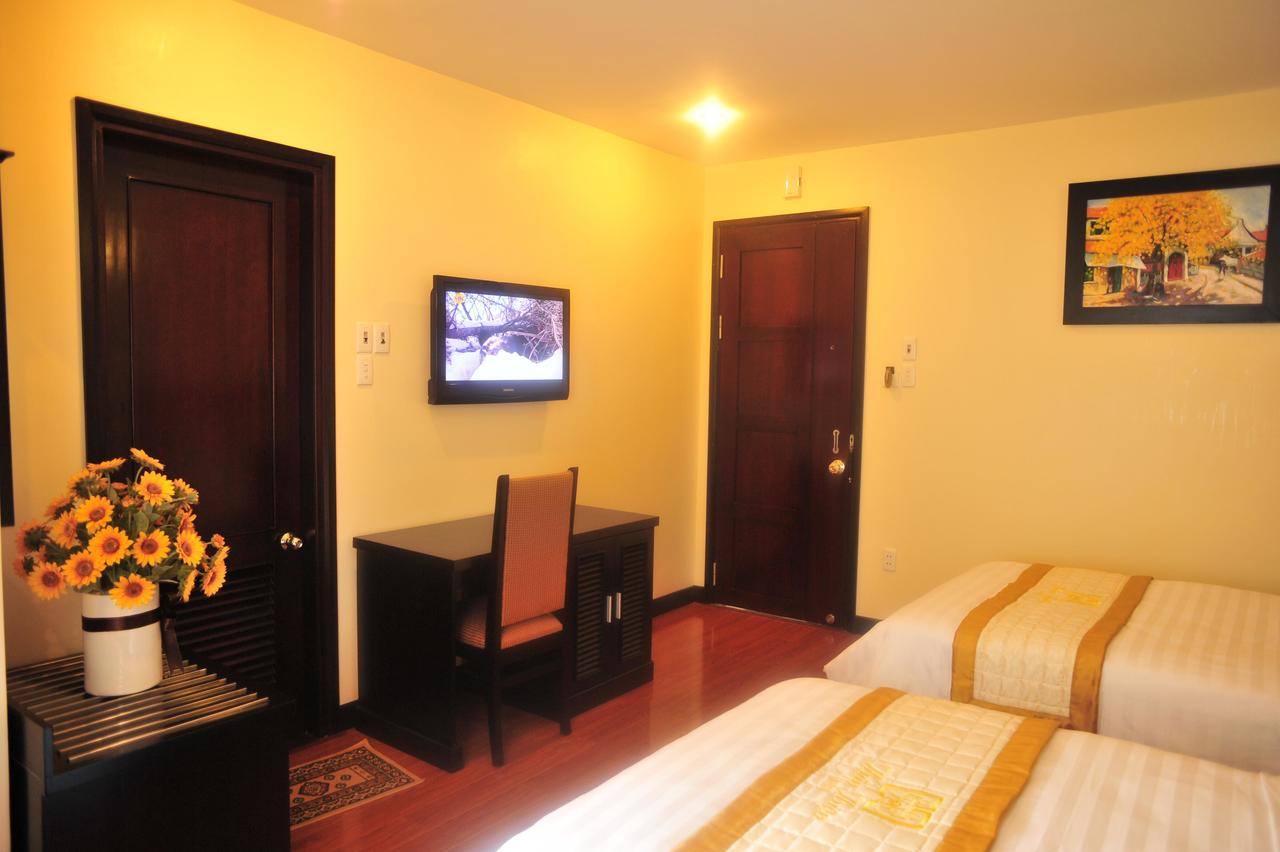 Nội thất phòng nghỉ ở Friendly Hotel gồm 2 giường, bàn, kệ, tivi, tranh treo tường, nhà vệ sinh khép kín