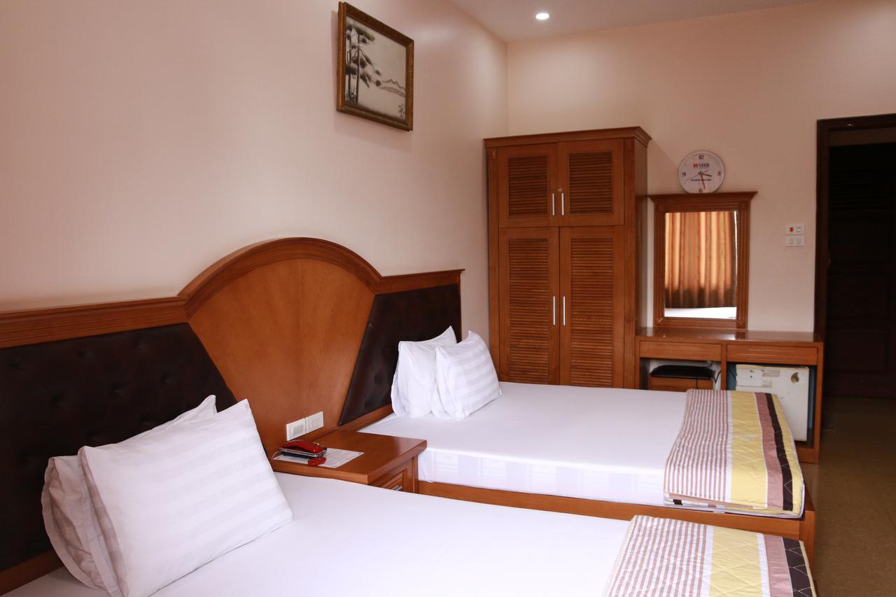 Phòng đôi 2 giường ở Van Nam Hotel có tủ gỗ, bàn trang điểm, tranh treo tường