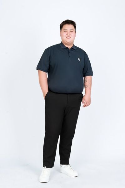 Người đàn ông béo mặc set đồ big size: Áo polo xanh navy kết hợp với quần âu đen và sneaker trắng