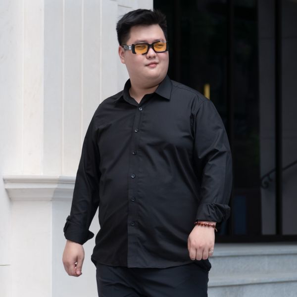 Người mẫu nam mặc áo sơ mi đen trơn dài tay big size nam, kết hợp với kính râm phong cách