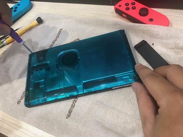 Nhân viên kỹ thuật bắt đầu thay ốp lưng trong suốt cho Nintendo Switch màu xanh ngọc