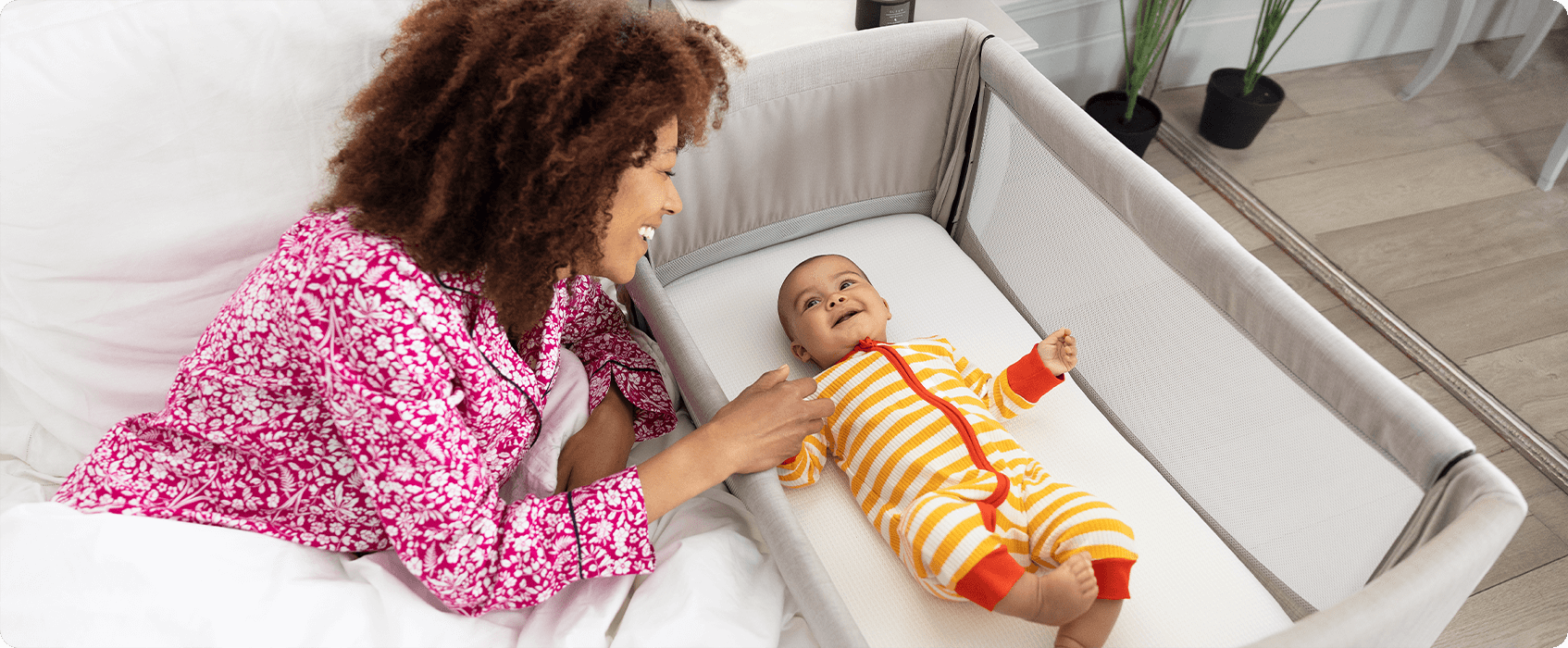 Mum sitting on the floor next to baby in the Joie Serina 2in1 baby swing