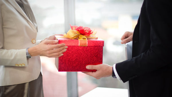Nhân viên nam tặng quà cho sếp trong không gian công sở sang trọng