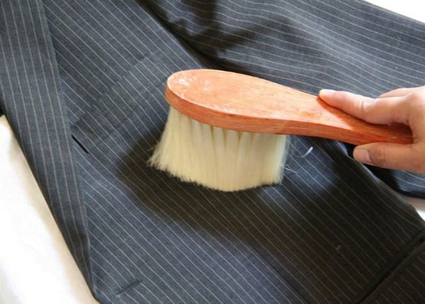 Dùng bàn chải lông mềm làm sạch những vết bẩn trên áo trước