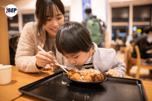 Mẹ và con trai thưởng thức bánh takoyaki