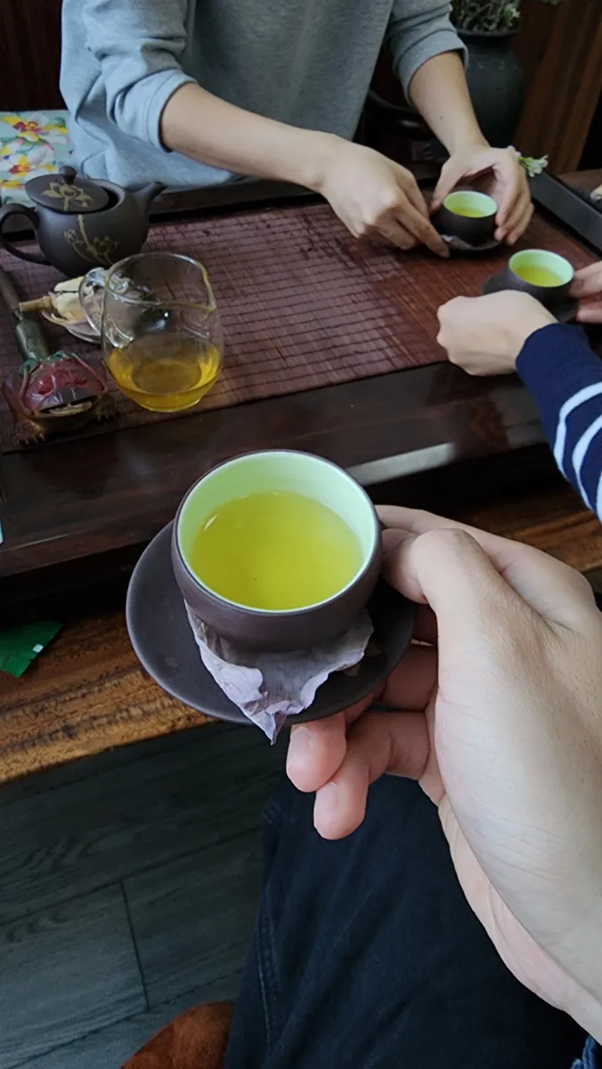 Cầm chén trà xanh trên chiếu tre