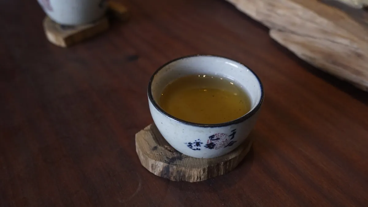 Chén trà trên đế gỗ – so sánh hương trà Việt Nam và trà Trung Quốc