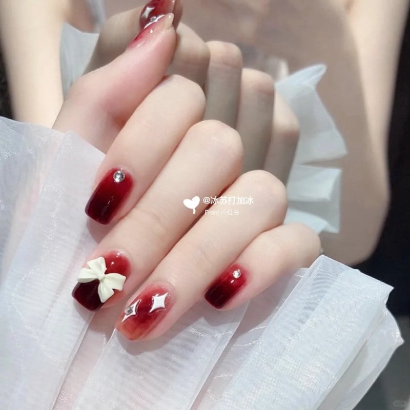 mẫu nail đỏ đô đính charm nơ