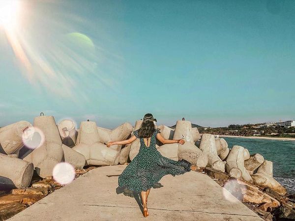 cô gái đứng giữa bãi đá ngoài biển