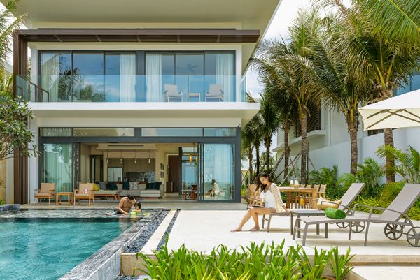 Biệt thự 2 tầng cửa kính, phía trước có hồ bơi và có người đang bơi