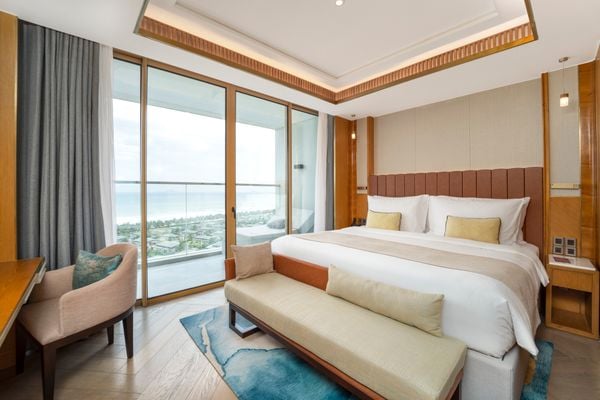 phòng deluxe suite có phòng ngủ hướng biển với giường đôi lớn, ghế sofa và ban công hướng biển