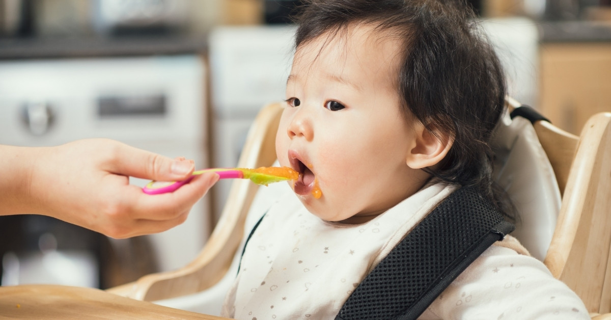 Khi bé ngồi thẳng, đặt thìa gần miệng bé, nhẹ nhàng đút thức ăn vào miệng bé
