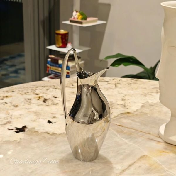Bình nước Georg Jensen Henning Koppel 1.2 Lít được làm bằng thép không gỉ và gây ấn tượng với hình dáng cong mềm mại.