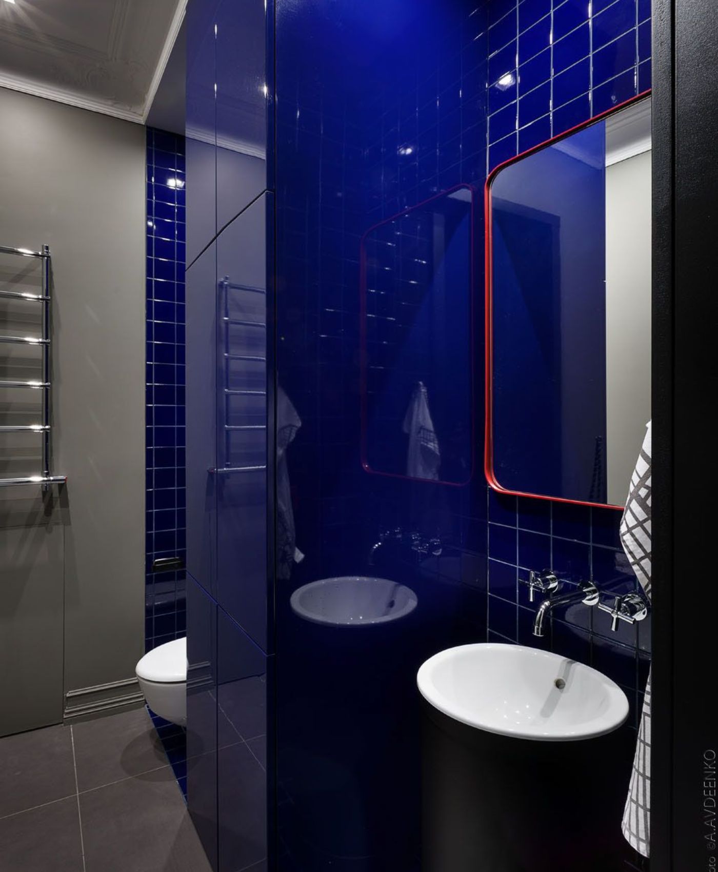 Nhà vệ sinh Tân cổ điển hiện đại với tường gạch xanh đậm, bồn rửa tròn trắng và chi tiết gương tròn viền đỏ nổi bật – thiết kế bởi TTCOM.