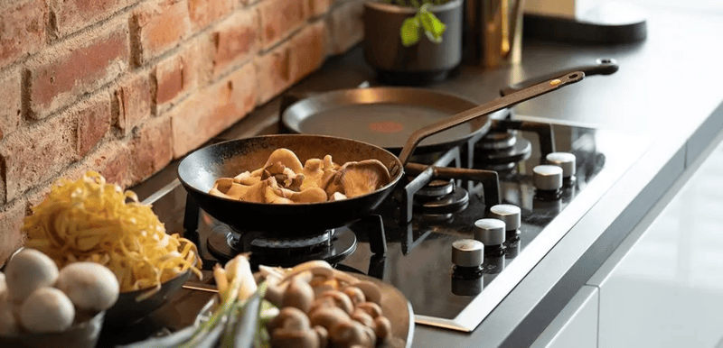 Chiếc chảo Fissler Cenit® màu đen đang chiên thức ăn trên bếp