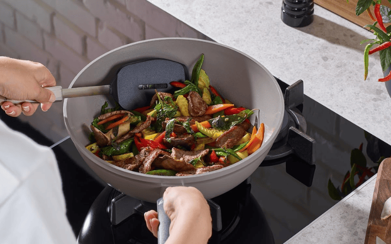 Chảo chống dính Fissler Ceratal màu xám nhạt đang chiên rau củ nhiều màu sắc, thể hiện sự an toàn và thân thiện với môi trường