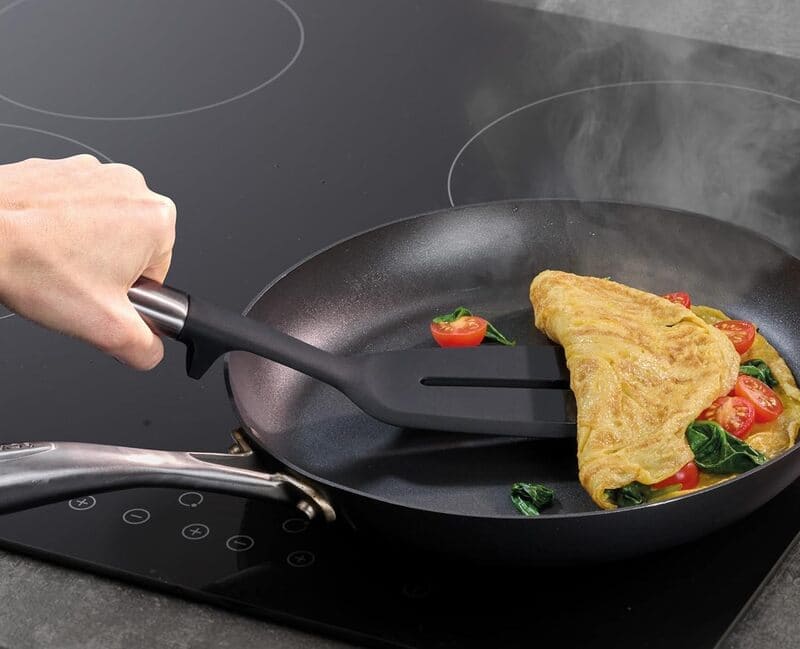 Đầu muôi và thìa silicone Joseph Joseph chịu nhiệt cao, đặt trên mặt bếp khi đang nấu nướng