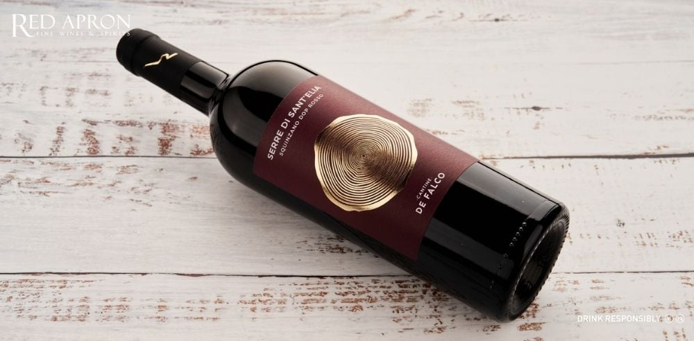 Chai rượu vang SERRE DI SANT’ELIA Squinzano DOP (Negroamaro blend), nhãn chai cận cảnh, nền đơn sắc.