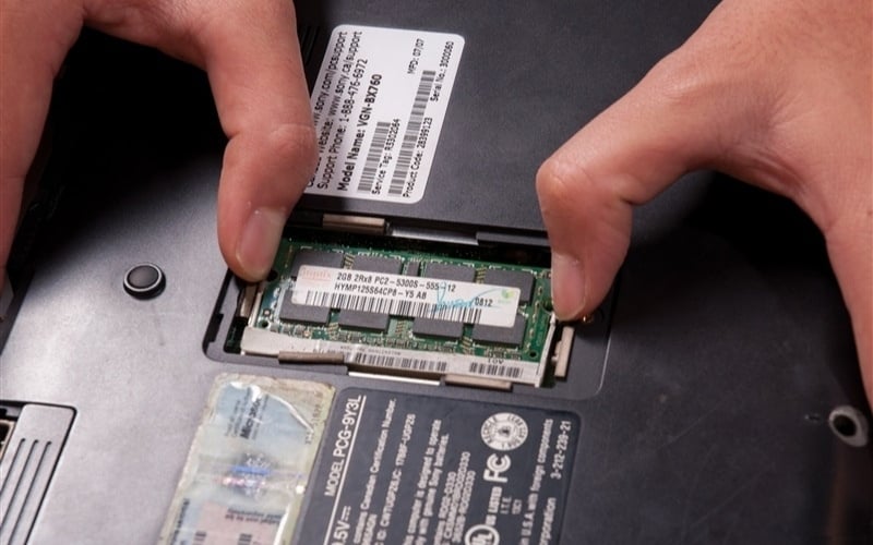 Dùng hai ngón tay nhẹ nhàng gạt hai lẫy kim loại ở hai cạnh thanh RAM ra ngoài