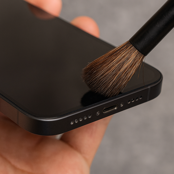 Cận cảnh người dùng vệ sinh lỗ mic iPhone bằng cọ mềm để loại bỏ bụi bẩn, dị vật.