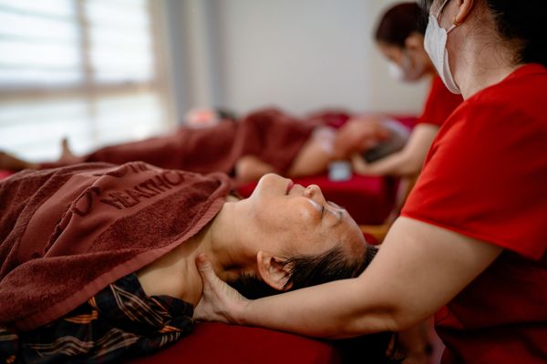 Kỹ thuật viên bấm huyệt trị liệu vùng vai cho người cao tuổi