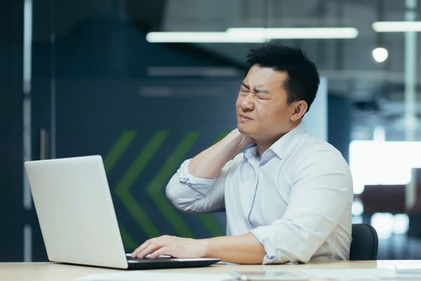 Nhân viên văn phòng ôm cổ vai, biểu cảm đau nhức